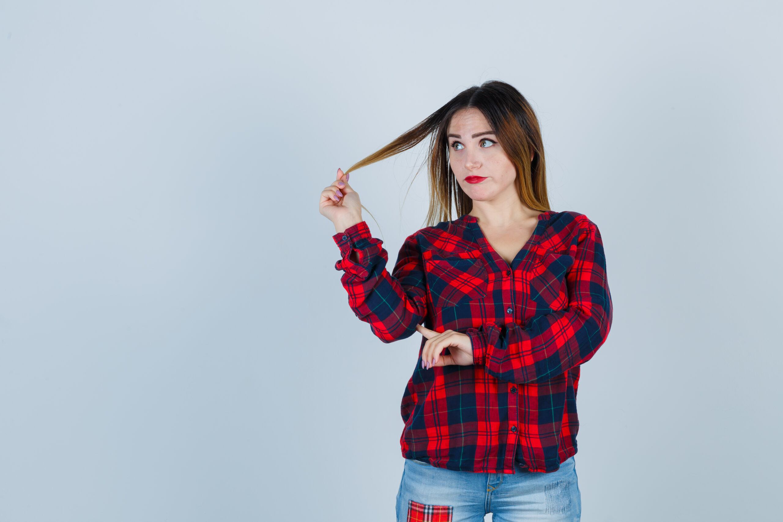 Portrait of young woman playing with her hair in checked shirt and looking pensive front view 18 Inch Halo Hair Extensions – 120g Natural Thickness - Image 5